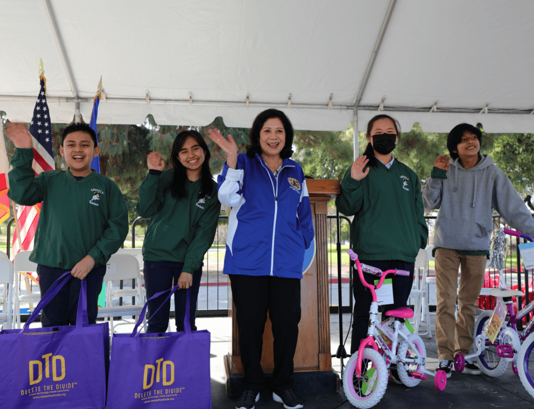 kids waving with tote bags and bikes