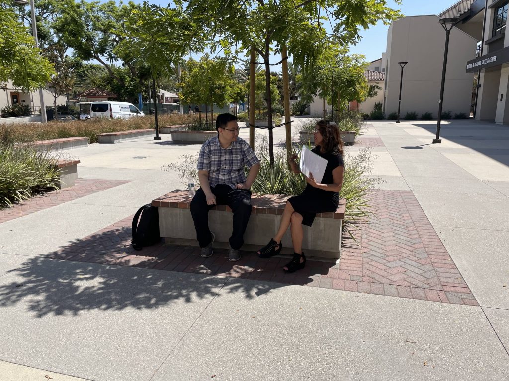 A man and lady talking sitting down on a bench.