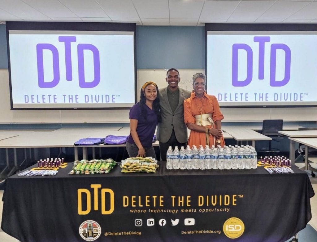 Program administrator, intern and a woman behind a Delete the Divide table.