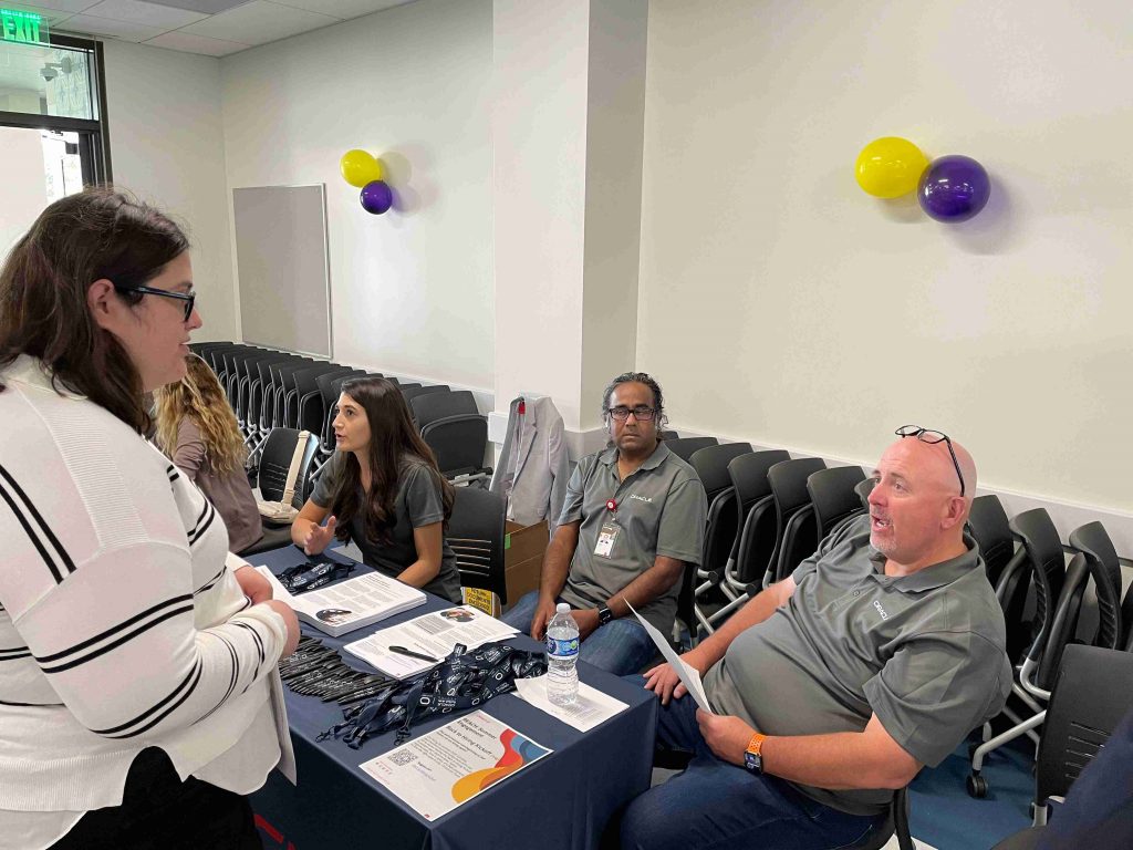 one female recruiter and two male recruiter interviewing female intern at booth