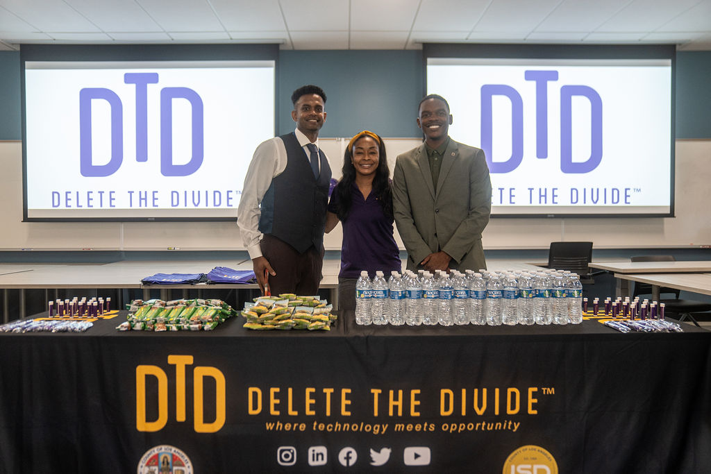 Delete the Divide Program administrators behind a table with goods and snacks on top.